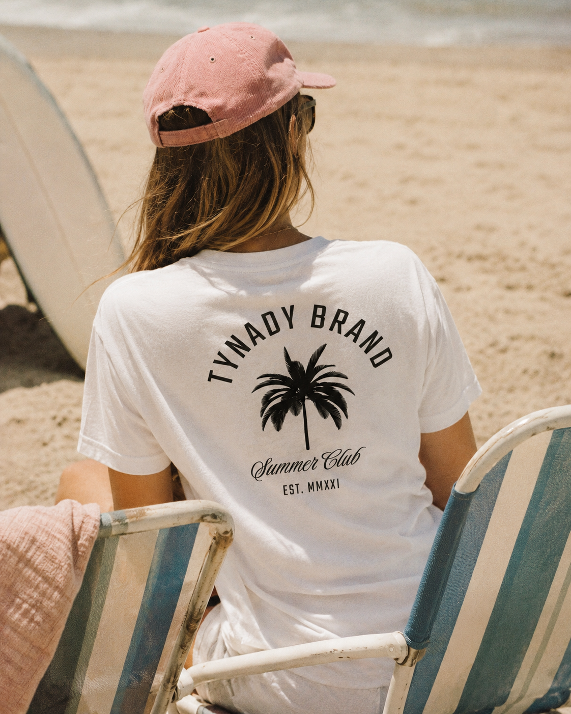 T-shirt branca Summer Club Tee Woman Tynady Brand 
— modelo costas — praia — palmeira — Chapter One EST. MMXXI